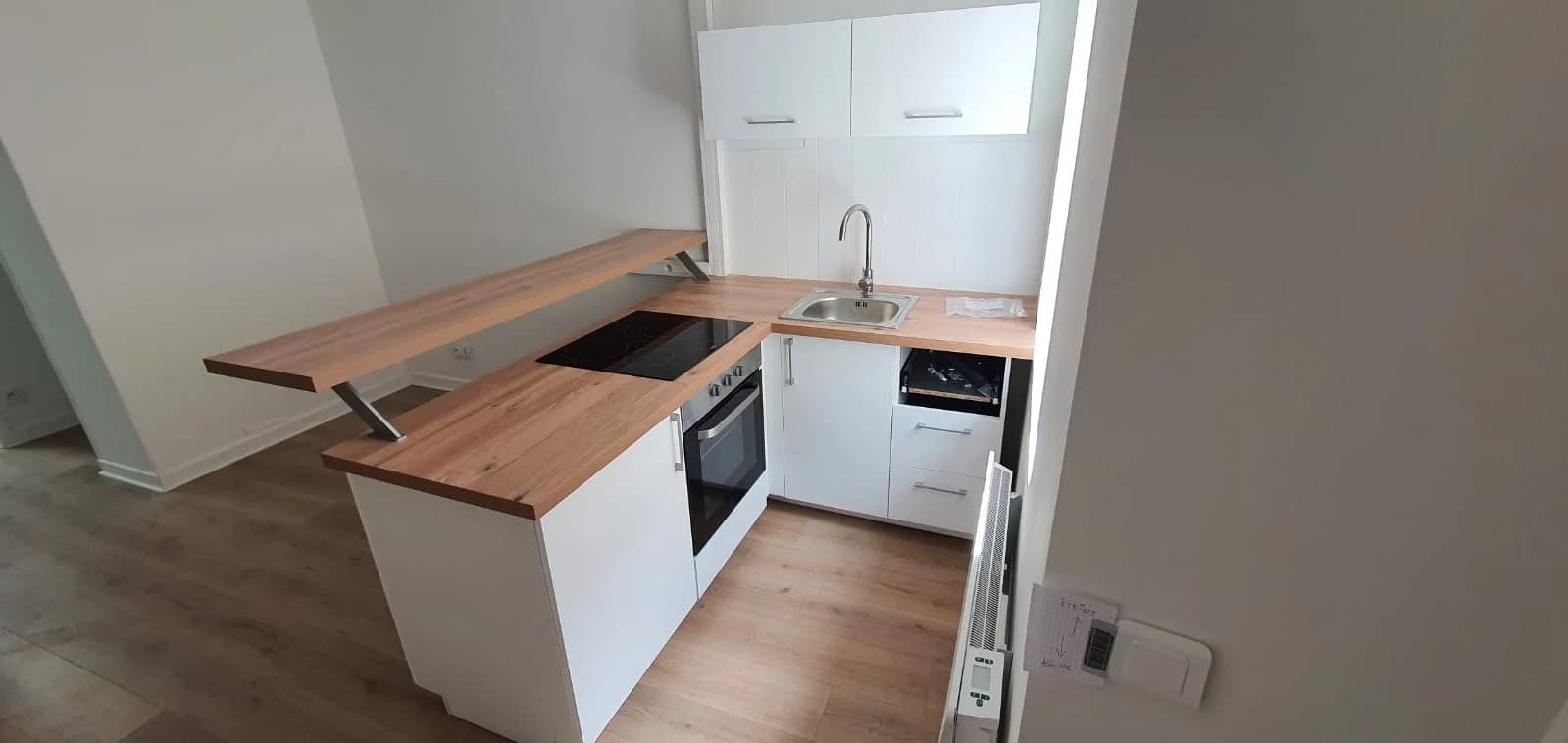 Cuisine ouverte blanche et bois dans l’immeuble Adrien rénové à Audincourt